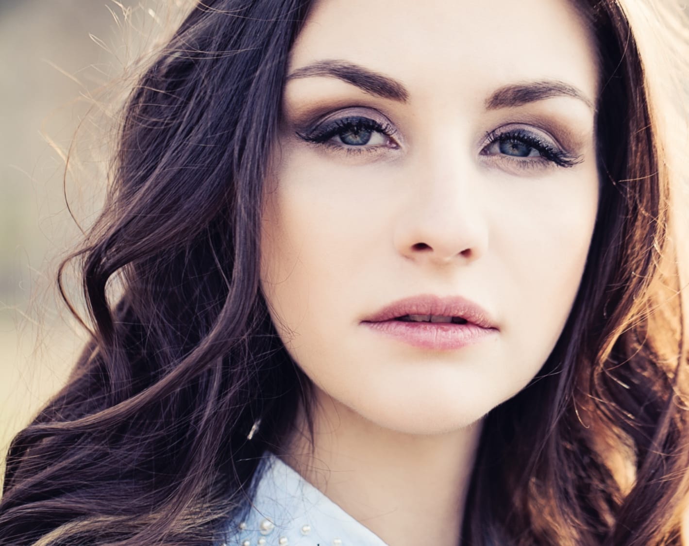 Woman with brown hair and smoky eyes with a serious expression