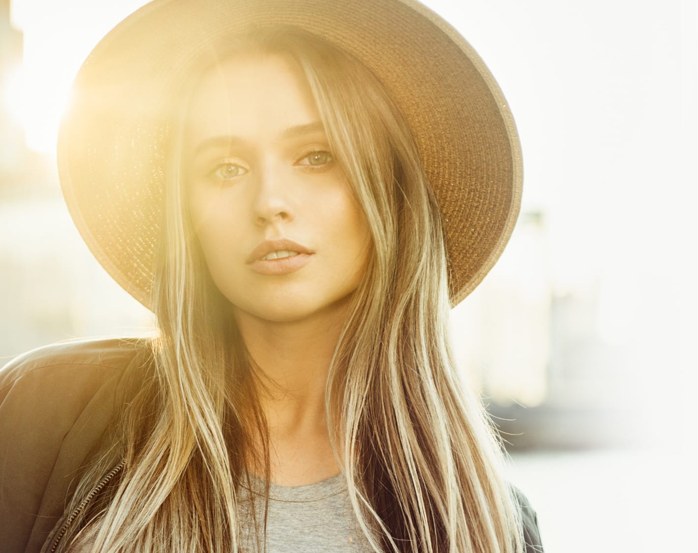 Woman wearing a large hat outside with the sun shining on her face